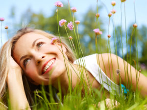 happy woman lying in flowers with straight teeth after braces