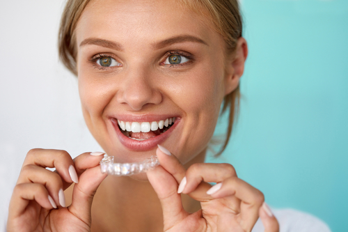 woman smiling holding clear dental trays
