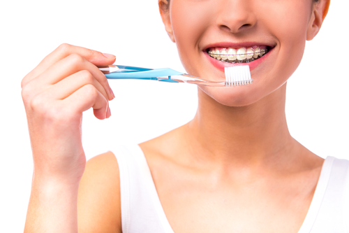 woman with braces on the teeth, cleans teeth with toothbrush, isolated on a white background