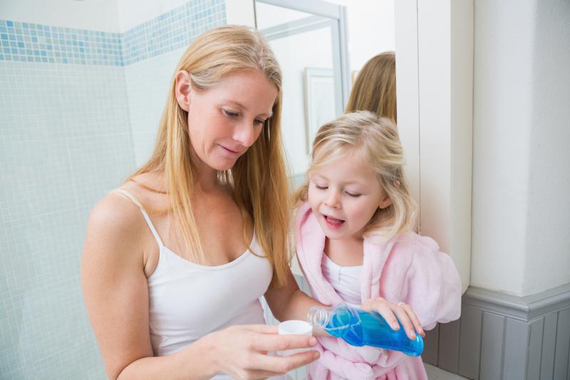 mother and child pouring mouthwash