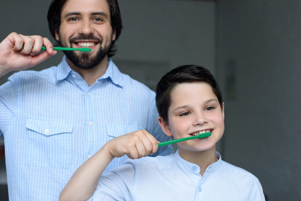 son and father brushing their teeth together