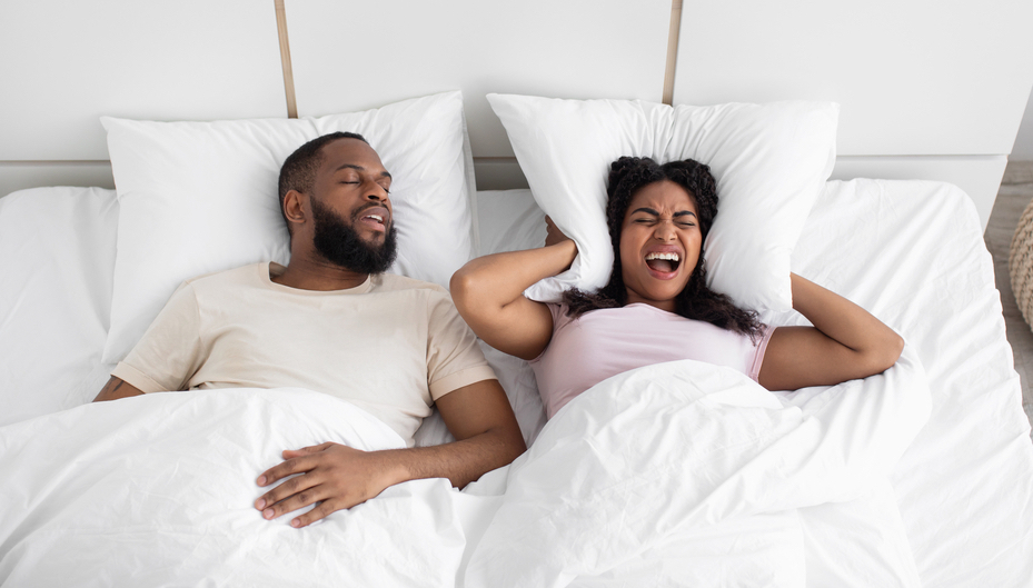 man snoring in bed with his wife awake