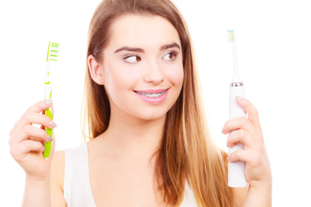 Woman with braces choosing between electric and traditional toothbrush