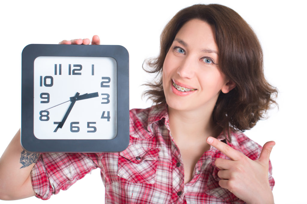 Girl with braces pointing at a clock