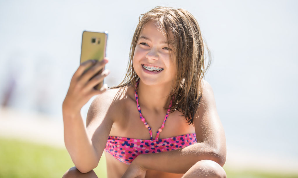 Girls smiling with braces at the beach in the summer. 
