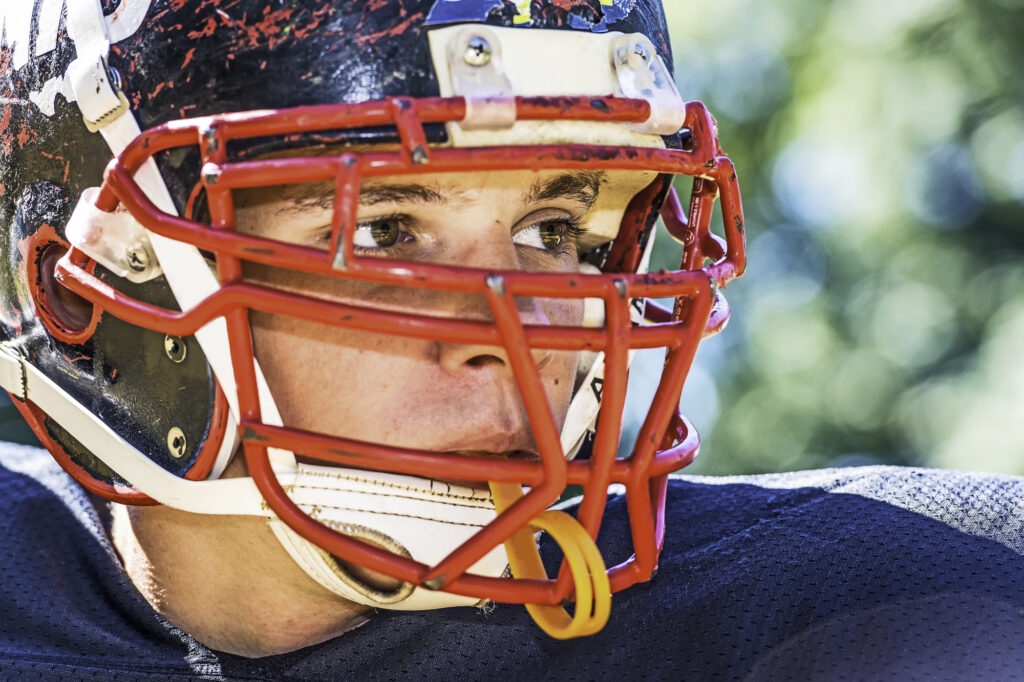 Teen playing football with braces mouthguard.