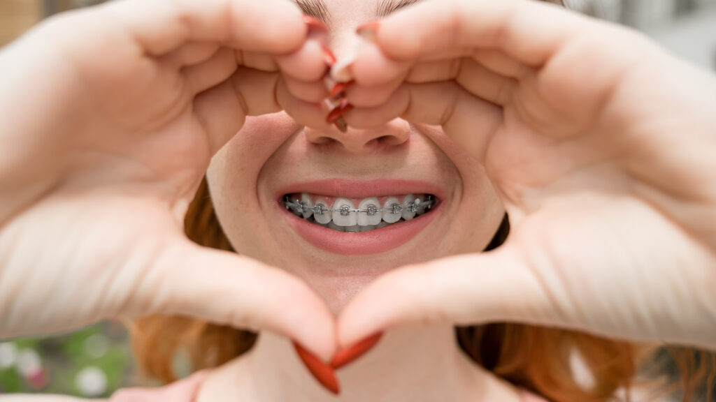 Woman holding hands like a heart in front of braces. 