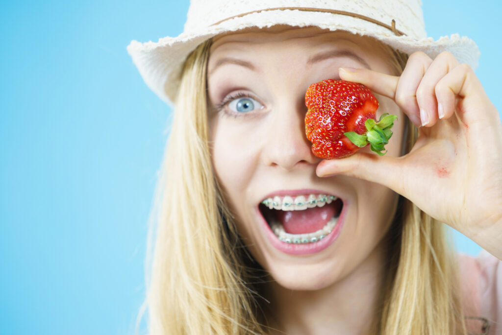 Woman with braces holding strawberries. 