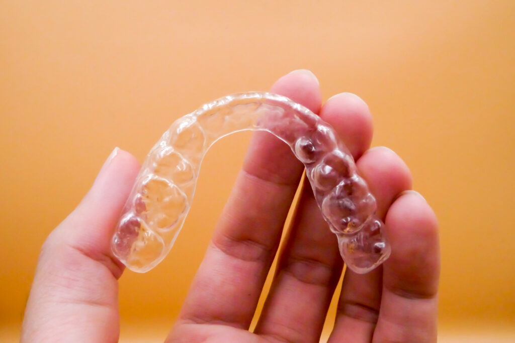 Hand holding invisible clear aligner