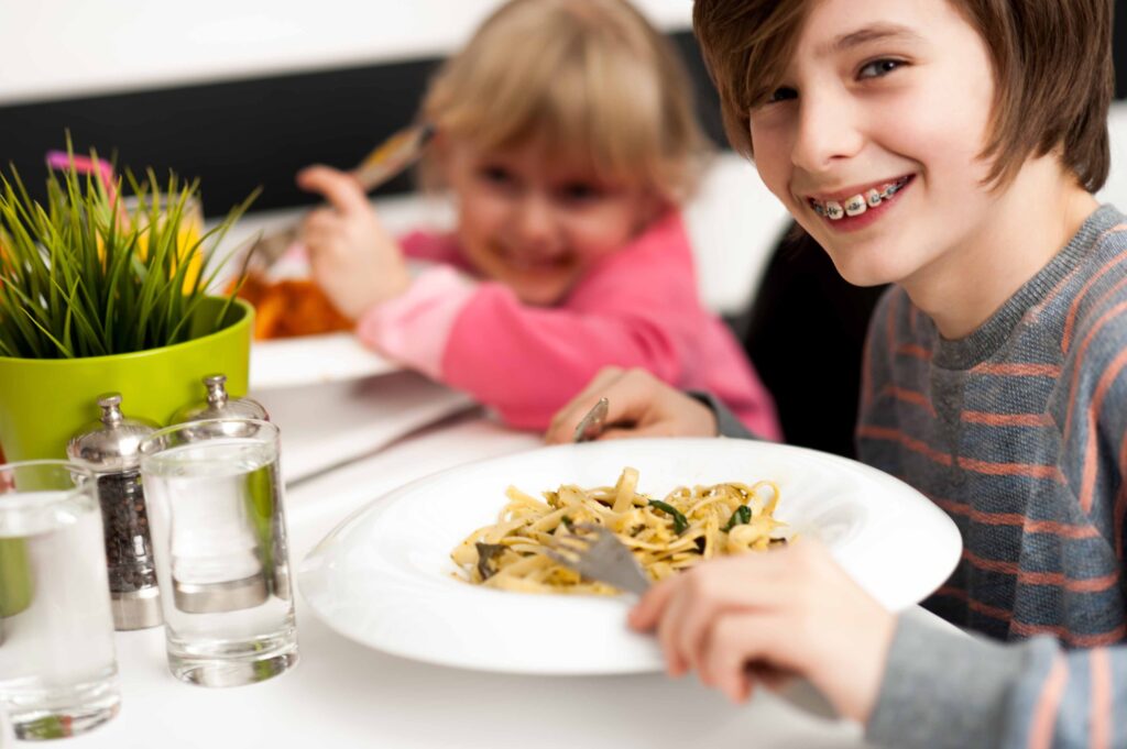 Child with braces enjoying a meal.