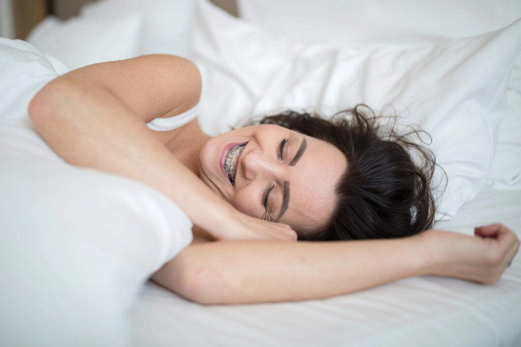Young woman with braces sleeping comfortably in bed.